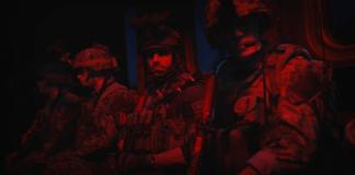 Three soldiers sitting side by side with red lighting in Modern Warfare 2